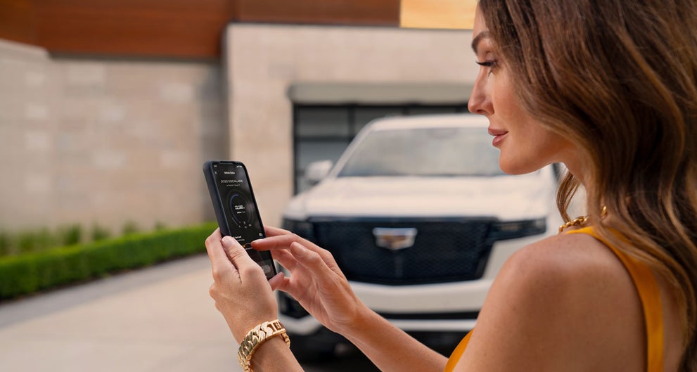 lady checking her mobile with a Cadillac vehicle background | Ed Morse Cadillac Tampa FL in TAMPA FL