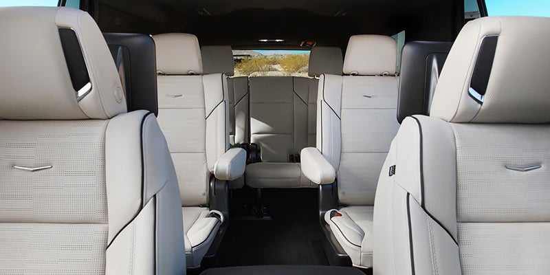 Interior of a Cadillac Escalade, featuring luxurious leather seats with detailed stitching, offering a spacious and premium feel