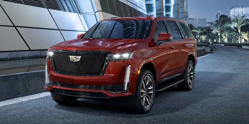 Red Cadillac Escalade driving on a road, showcasing its bold color and sleek design in motion