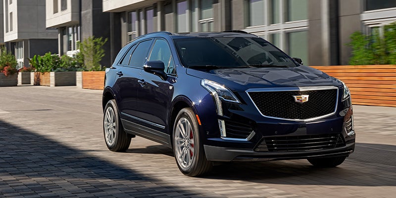 Cadillac XT5 driving on a road, showcasing its smooth motion and stylish design.